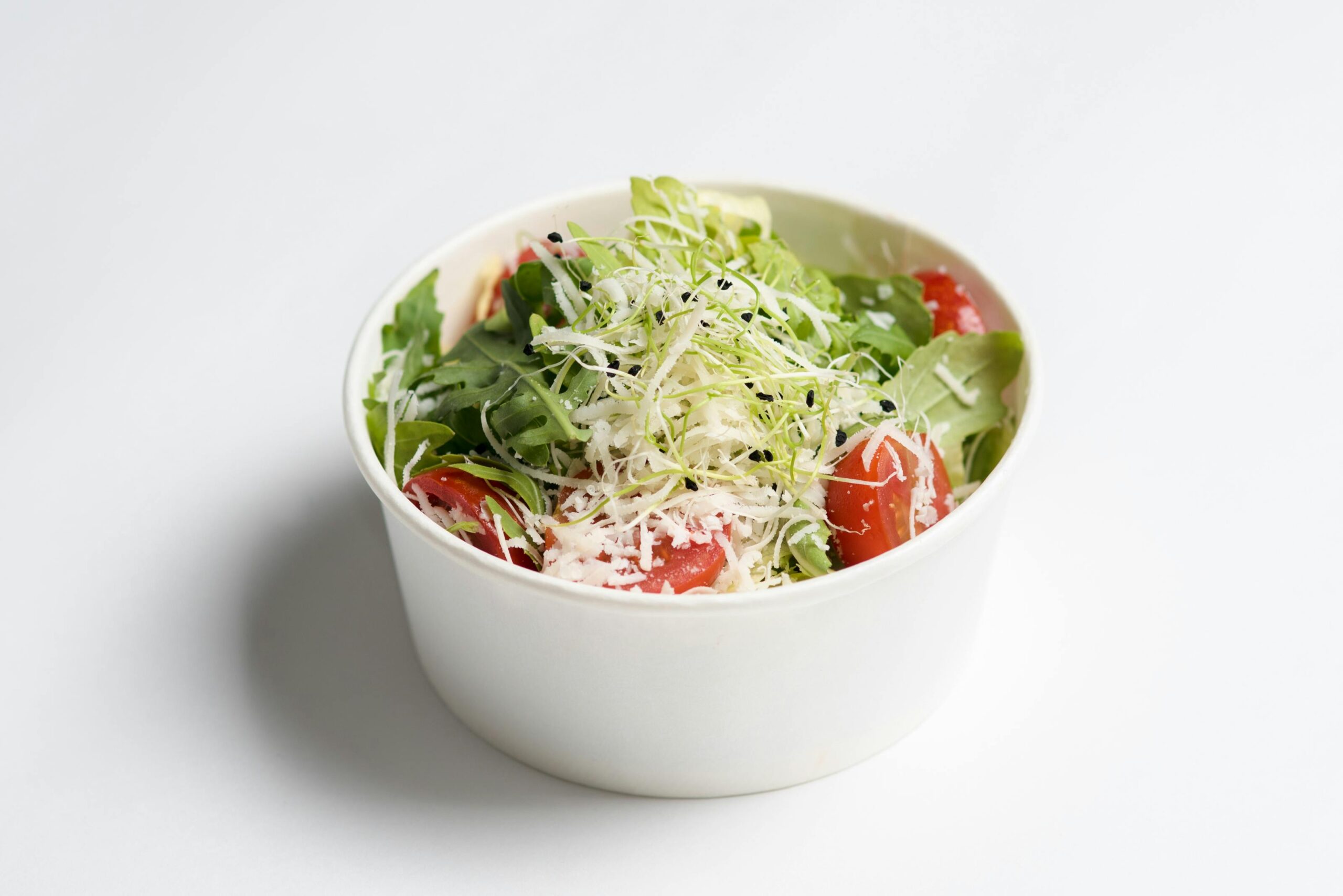 Delicious garden salad featuring cherry tomatoes, greens, and grated cheese in a bowl.